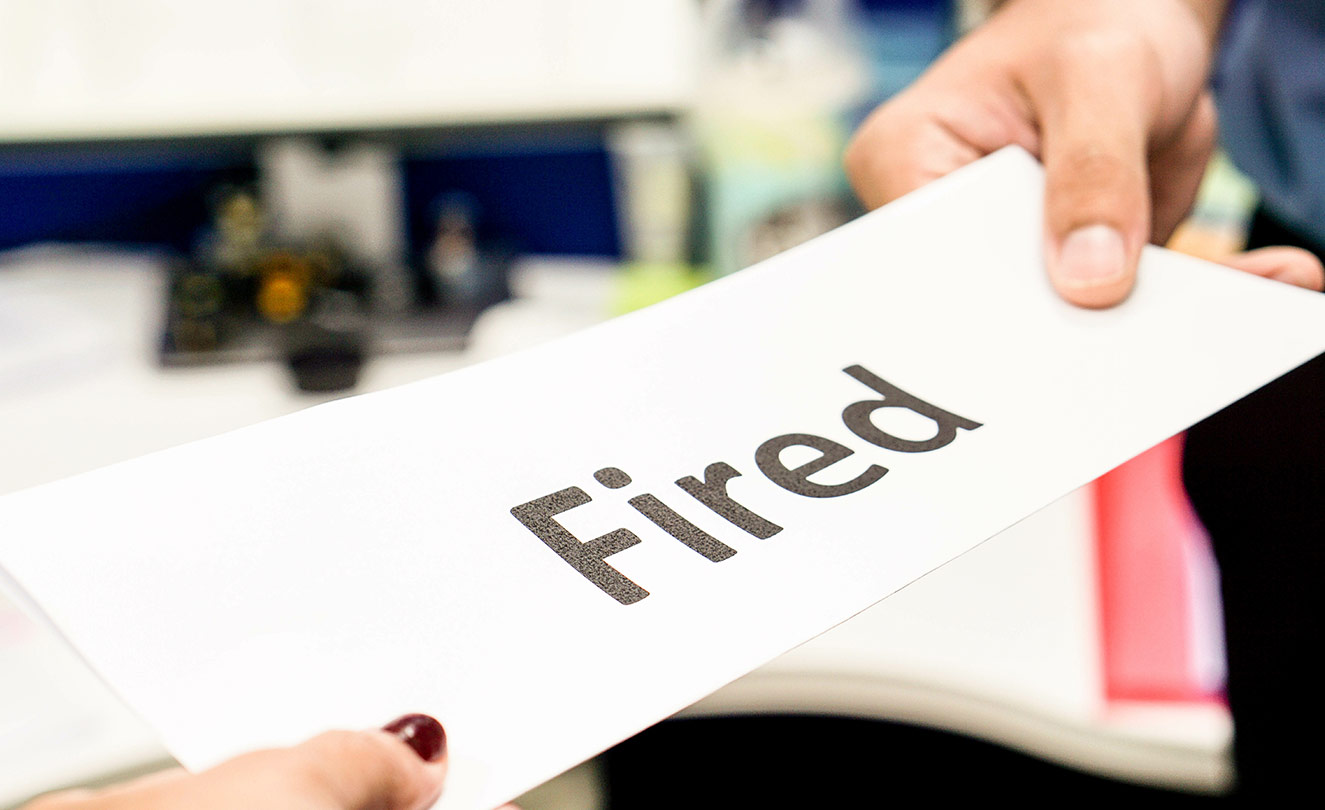 Women holding a rectangle piece of paper that says 'Fired'